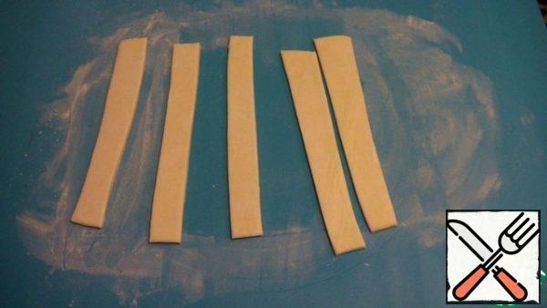 The second layer is rolled out with a thickness of 5 mm, and cut it into strips with a width of 1.5-2 cm. This will be the sides of our pie.