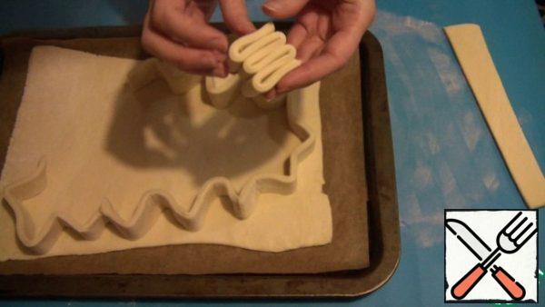 Each strip is folded with an accordion, and spread on the first layer of dough so that it looks like a Christmas tree, cut off the excess dough.