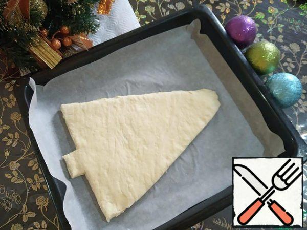 Layer of dough with condensed milk cover the second layer of dough, put on a baking sheet, covered with parchment paper. Cut the workpiece, giving the shape of a triangle.