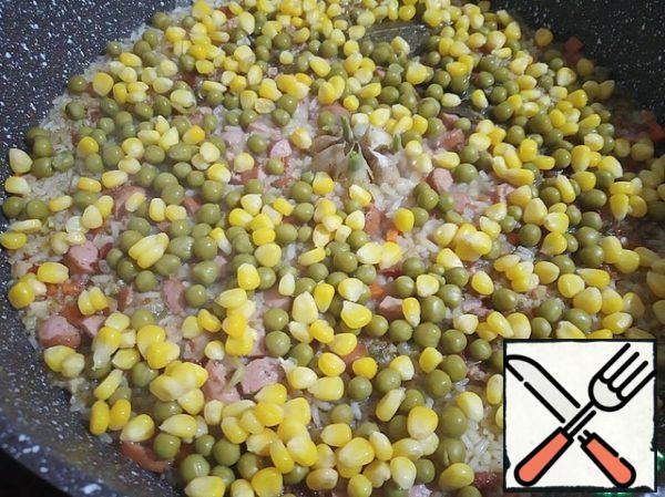 After the water boils a little - there will be almost no water over the rice, pour the peas and corn on top.