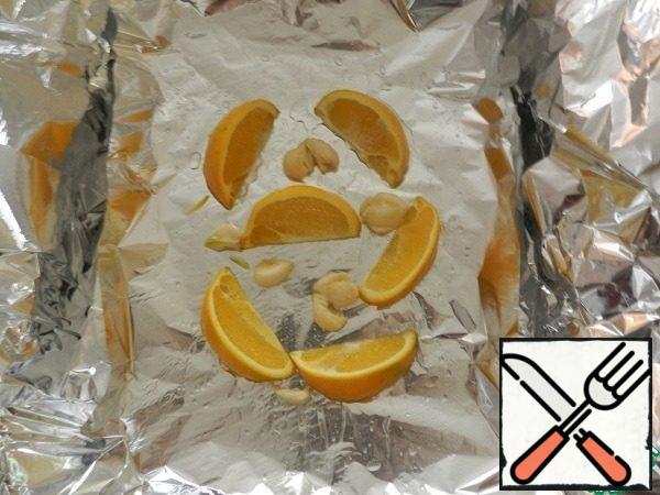 Build a foil tray: Put two sheets of foil horizontally, one sheet on top of the other vertically, slightly bending the edges to get a kind of "bath". Grease the foil with a little oil. Put the garlic with the oranges.