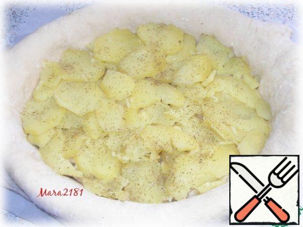 The next layer will be potatoes again. Carefully lay out the remaining sliced potatoes. Again, sprinkle the Khmeli-suneli hops to taste and distribute the pieces of butter (30 g).