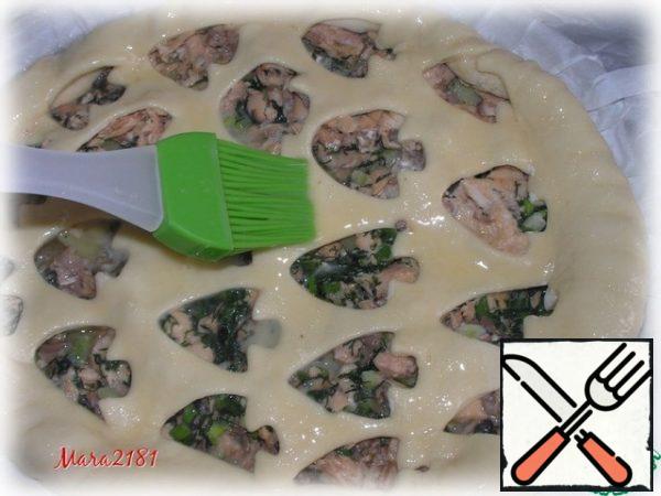 I cover the surface of the pie with the prepared dough and gently pinch the edges. Beat 1 egg and smear it on the surface of the cake.
