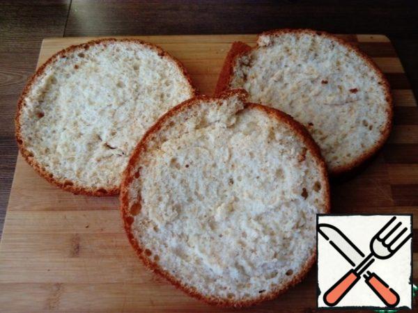 Prepare a sponge cake.
- Beat the eggs with sugar until the volume increases two to three times.
- Add parts of the sifted flour to the beaten eggs, gently mix the mass from top to bottom with a wooden or silicone spatula. The dough should be airy. We try not to let the dough fall off.
Transfer the dough to a greased baking dish.
Put in a preheated 180 * C oven for 25-30 minutes (check readiness with a toothpick).
The biscuit mold has a diameter of 18 cm.
- After the biscuit is baked, put it on a board and let it cool completely.
Then the cooled sponge cake is cut into three cakes, the top of the biscuit is also cut off.