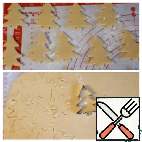 Roll out the dough with a thickness of 0.5 cm and cut out the Christmas tree shape.