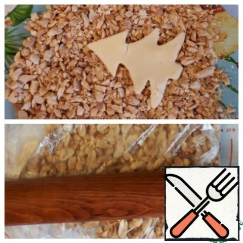 Nuts pre-dry and peel, chop them with a rolling pin. Cut out the figure to grease with protein or egg, sprinkle with nuts.