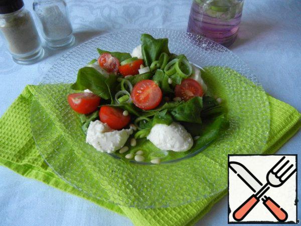 Put the spinach, cherry and mini mozzarella on a plate with the remaining onion. Sprinkle the salad with pine nuts and pour the dressing.