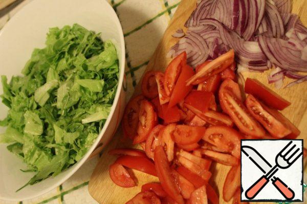 Tear the lettuce leaves with your hands, cut the tomatoes into thin slices, the onion into four parts and then as thin as possible.