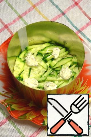 Put all the ingredients in layers in a salad bowl. However, I have a homemade mold, cut out a piece of a liter beer can, painted with spray paint, hand made, so to speak
First, thinly sliced cucumber, you can add a little salt, add a little sauce.