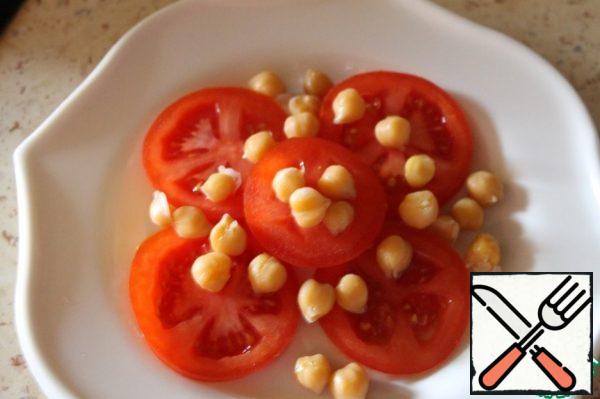 Spread the rings of tomatoes on a plate, sprinkle with chickpeas, salt, pepper.