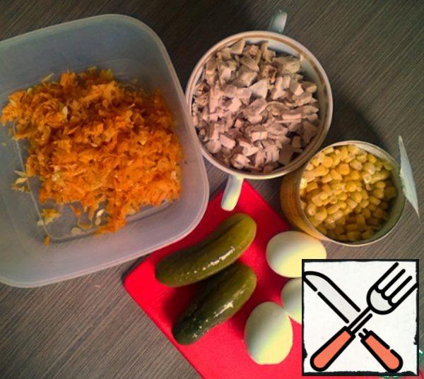Cook and chop the eggs. Cut the cucumbers. Mix with chicken, carrots and onions, corn.