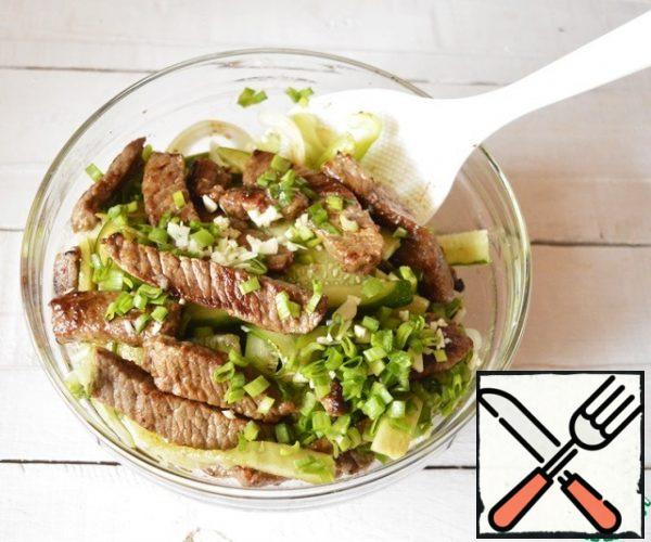 The finished meat is sent to the vegetables and add cucumbers there, after squeezing out the excess liquid and blotting with a paper towel.
Add finely chopped garlic and green onions, wine vinegar and soy sauce.
Carefully mix the salad, cover with cling film and send it to the refrigerator for 30 minutes.