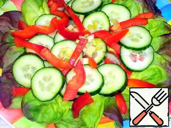 She arranged the lettuce leaves on a large platter.
Bulgarian pepper cut into thin slices and put on the leaves.
Cucumbers are cut into circles and spread on top of the pepper.
And so in two layers.