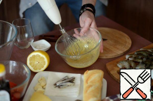 Prepare the salad dressing: separate the egg yolks and start whipping them with mustard, gradually adding olive oil, use classic olive oil, extra virgin will spoil the taste of the dressing. Then add salt to the anchovy fillet (you can also use a sprat of hot salt), grate the garlic on a fine grater, add it to the mixture, continuing to beat. The gas station is ready. In consistency, it should resemble liquid sour cream.