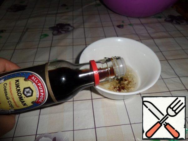 Pour garlic oil into a cup, add garlic, a pinch of ground black pepper and soy sauce. Mix well.