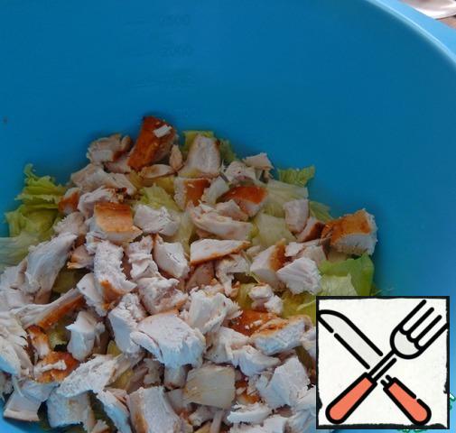 Lettuce leaves  is torn into pieces, chicken breast is cut , kiwi is cleaned and cut, everything is mixed in a salad bowl.