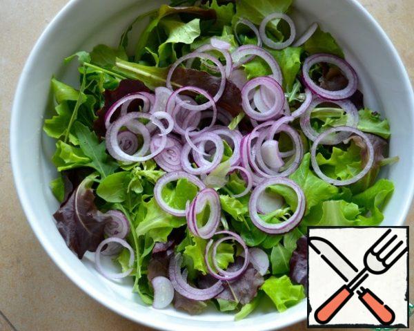 Peel the red onion and cut it very thinly into circles or half- rings. Add to the greens.