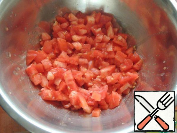 Meanwhile, dice the tomatoes into a separate bowl. Squeeze the garlic through the press and chop the greens with a knife.