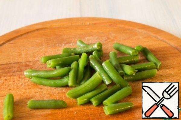 Defrost the string beans and lightly blanch them in hot water. Make sure that it does not lose its color.