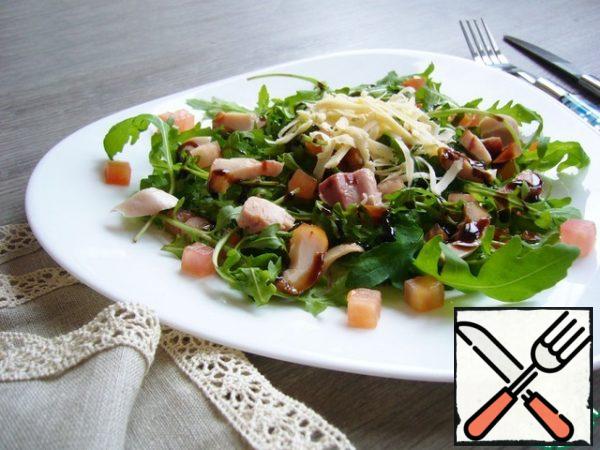 Put the arugula, tomato and ham on a plate. Sprinkle cheese on top and season the salad with balsamic sauce.