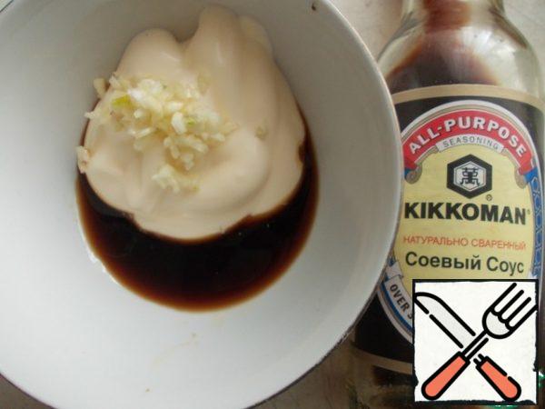 Prepare the sauce. RUB the garlic clove into the mayonnaise and pour the soy sauce. Stir well.