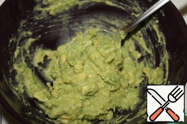 Peel the avocado, remove the stone, put it in a small bowl, sprinkle with lemon juice and mash it with a fork .