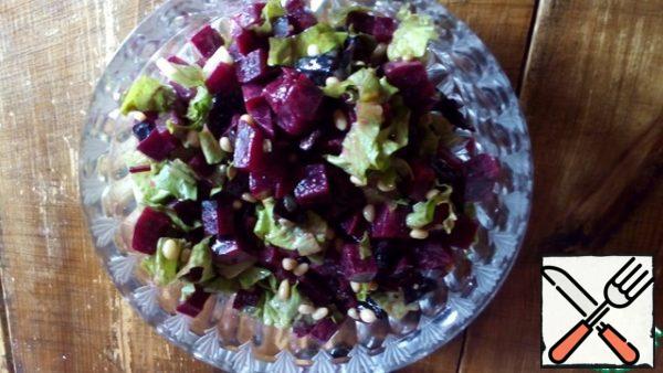 Mix beets, prunes, coarsely chopped lettuce leaves, pour dressing, sprinkle with pine nuts.
