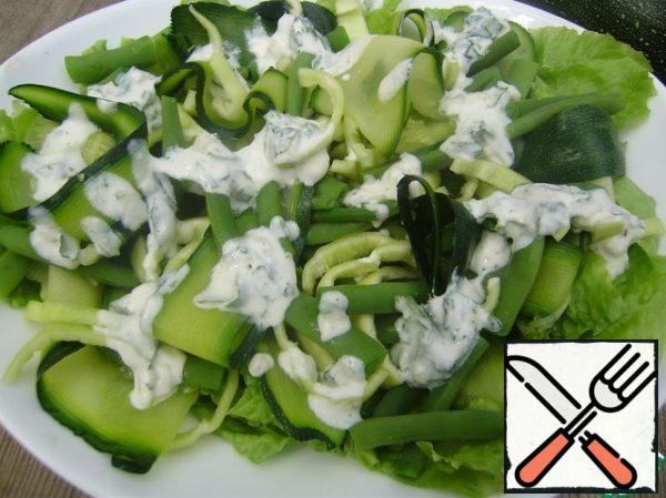 Prepare the dressing. Finely chop the garlic and mint. Add to the yogurt, season with salt and pepper to taste. Put the salad on a plate and pour the dressing over it.