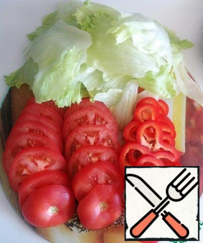 The peppers and tomatoes to slice. Tear the lettuce leaves into small pieces with your hands.