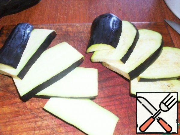 Wash eggplant, remove the stalk. Cut in half across. Then each half is cut into plates a little less than a centimeter thick.
The plates are cut into strips-bars also a little less than a centimeter thick.