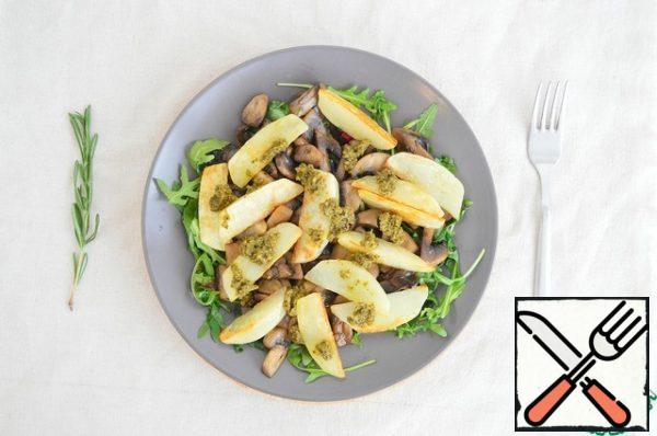 Put the arugula on the dish, top with the fried potatoes and mushrooms. Season with pesto sauce.