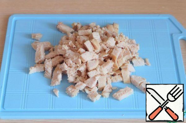 Boil the chicken fillet and cut it into cubes.