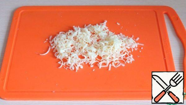 Grate the hard cheese on a grater with small straws.