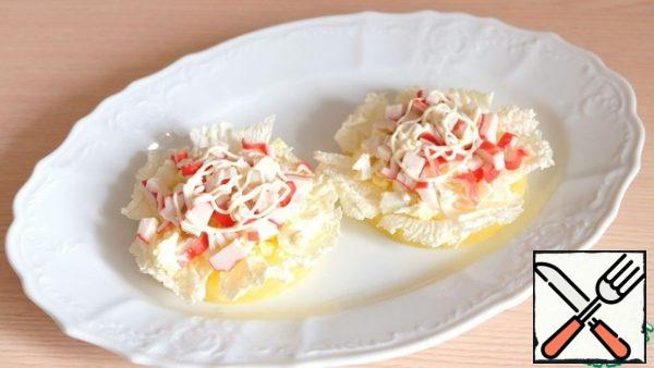 Next, put a layer of chopped crab sticks. Brush lightly with mayonnaise.
