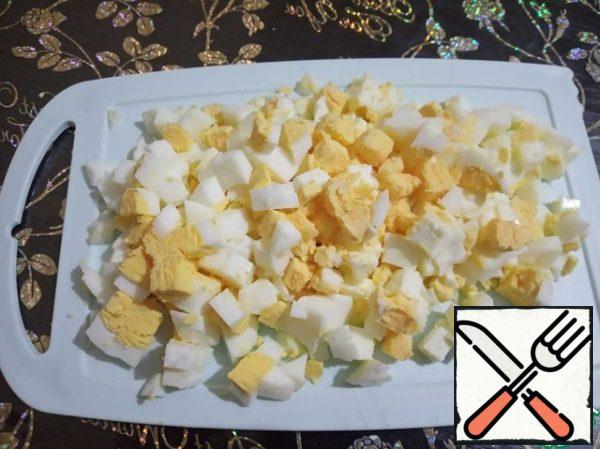 Cut the boiled eggs into small cubes .