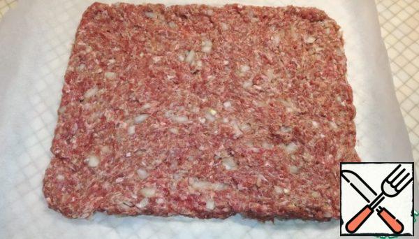 On a sheet of parchment, we form a rectangle of minced meat, I have 25 × 30 cm.