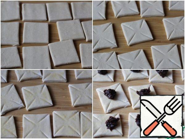 Preheat the oven to 175°C. cover the baking Sheet with baking paper .
Cut the dough into 15 squares measuring 6x6 cm. make diagonal cuts on each square from the corner to the middle, leaving 1 cm in the center.
Using a brush, brush each square with beaten egg, then put 1 tsp of filling in the center.