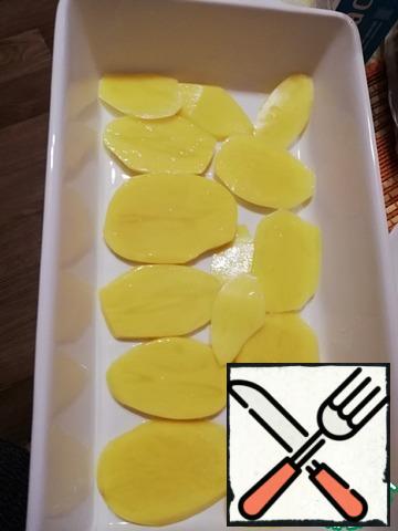 Grease the baking dish with oil and put the potato slices. Lightly salt the potatoes. This will not allow the fish to dry in the oven, and potatoes are perfect as a side dish.