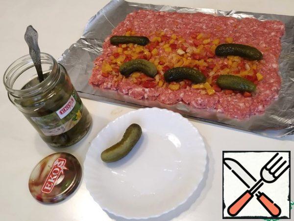 Put the onion and pepper filling on the minced meat. Distribute the cucumbers, they can be cut lengthwise.