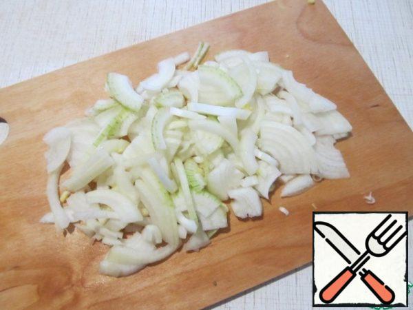 While the fish is marinating, turn on the oven and prepare the vegetables.
Peel the onion and cut it into half rings.