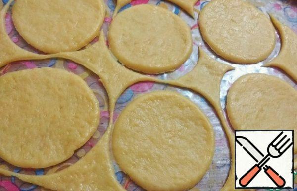 Roll out the dough into a thin layer.
Cut out circles in diameter with a glass so that they are larger than cupcake molds.