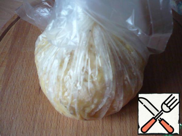 Now take the ends of the plastic wrap to cover the top of the potato mass stuffing from minced meat. Twist the ends of the food wrap so that you get a potato ball.