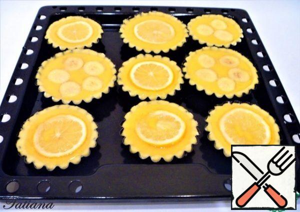 Pour the remaining sugar into a saucer, dip a lemon slice in the sugar, and place it on top of the tangerine filling. Do the same with banana rings.