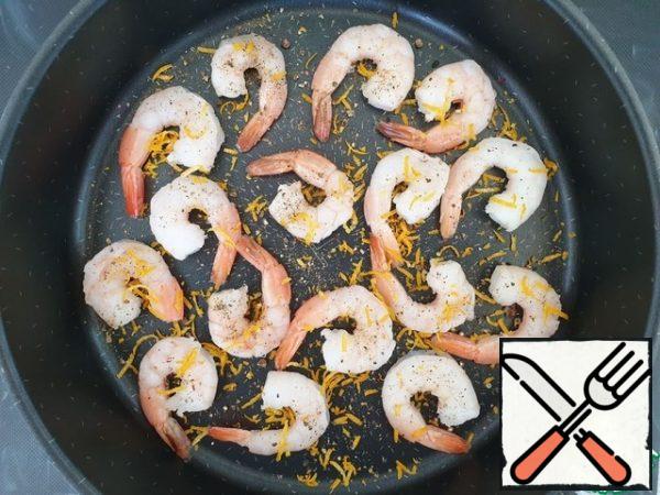 Prawns in my case are boiled and frozen. Defrost them, clean them , put them on a baking sheet . Add salt and pepper to taste and sprinkle with lemon zest. Drizzle with olive oil.
Send the shrimp in a preheated 180*C for 5 minutes .
