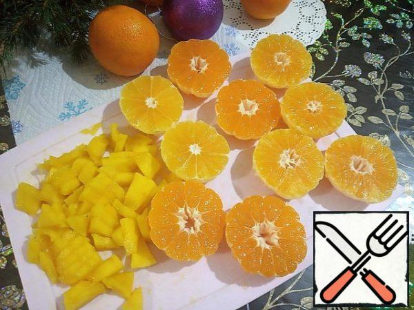 Peel the tangerines and cut them in half. The peeled half of the mango is cut into small arbitrary pieces.