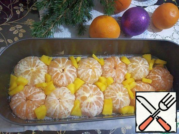 At the bottom of the form, put the halves of tangerines cut down. The gaps between the tangerines are filled with mango slices ( a small part of the mango is left, do not put it).