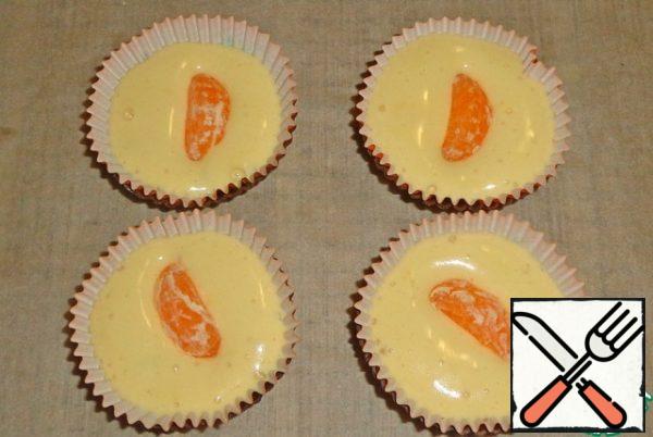 Pour the dough into paper molds. Put a slice of tangerine in each mold. Place in a preheated 180 degree oven and cook for 25 minutes.