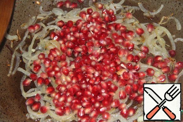 Add the pomegranate seeds to the onion and fry for about a minute, stirring as well.