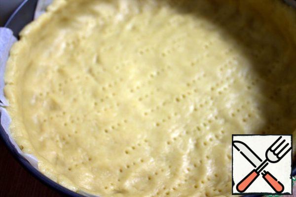 Separate part of the dough for the top, and distribute the rest along the bottom of the mold (which is covered with parchment) and form the sides. Prick the bottom with a fork. We send the form to the refrigerator while we prepare the filling.