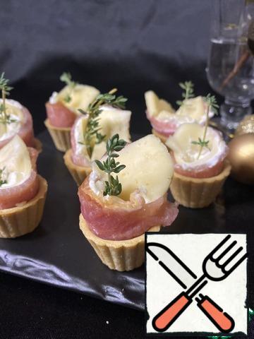 Put a little cheese filling down the tartlets. Roll up the spiral and install the cheese and meat "construction". Garnish with herbs.
